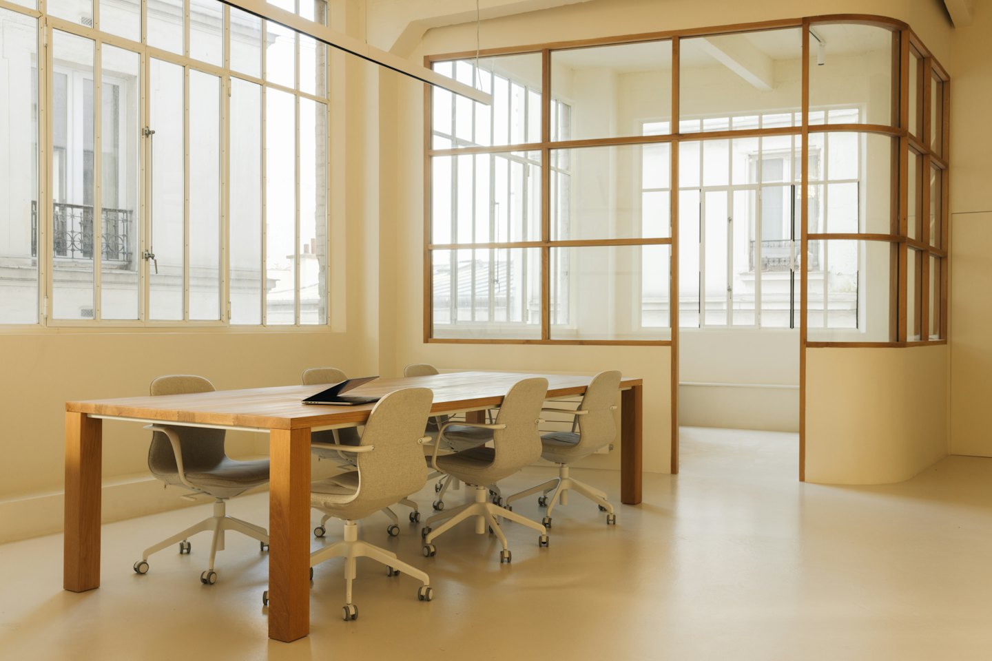 Sala de reuniones moderna vacía con mesa de madera y seis sillas.